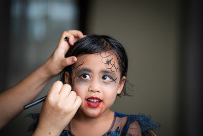 Mother painting daughters face. halloween party.
