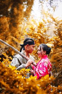 Couple in traditional clothing with sword standing at forest