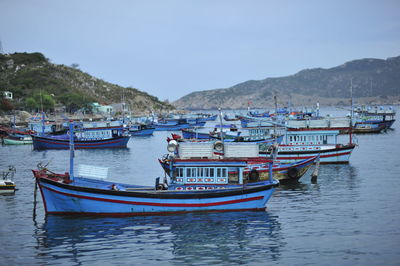 Boats moored in sea against clear sky