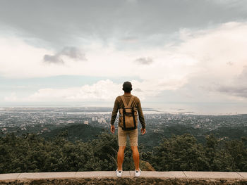 Rear view of man looking at cityscape against sky