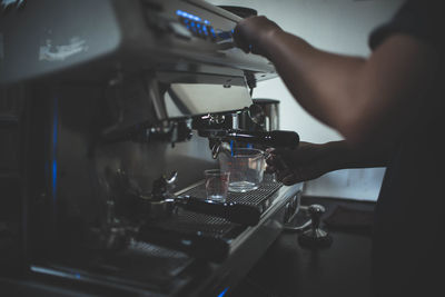 Midsection of person preparing coffee in cafe