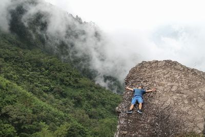 High angle view of hiker relaxing on mountain during foggy weather