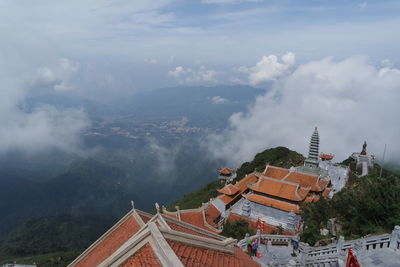 Panoramic view of buildings and mountains against cloudy sky