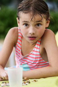 Portrait of wet girl lying on sand at beach