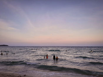 People on beach against sky during sunset