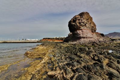 Rock formations in sea against cloudy sky