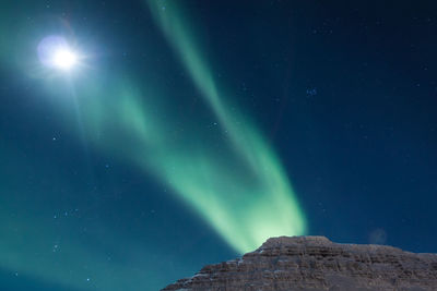 Aurora borealis and moon at highland landscape photo