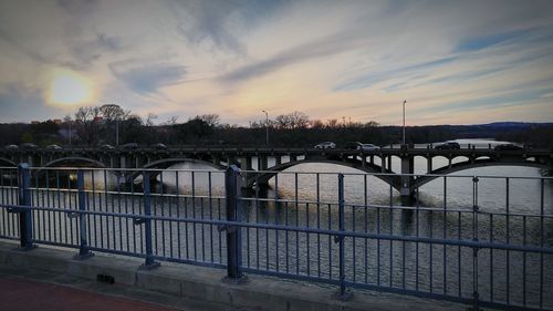 Bridge over river against sunset sky