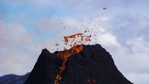 Low angle view of fire on mountain against sky