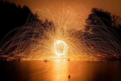 Firework display over river against sky at night