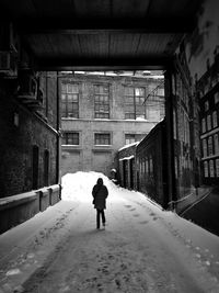 Full length rear view of woman walking in snow covered buildings