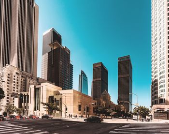 View of city street and buildings against blue sky