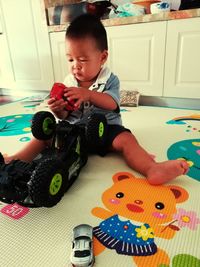 Boy playing with toy on bed at home