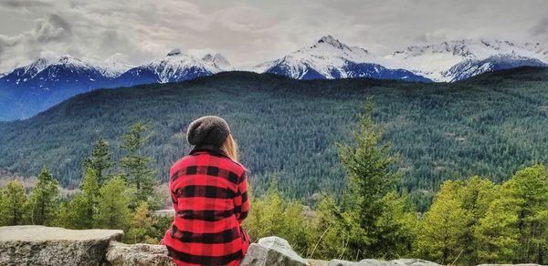 Rear view of person looking at mountains against sky