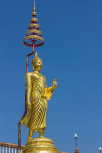 Low angle view of statue against temple against clear blue sky