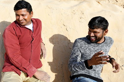 Smiling young man sitting on the beach