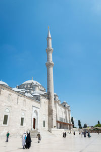 Group of people in front of historic building against blue sky