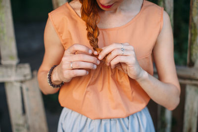 Midsection of woman braiding hair