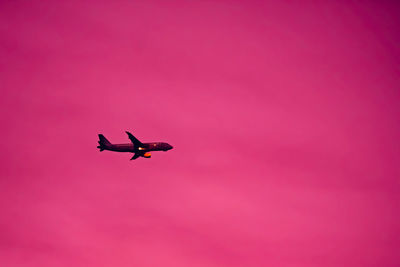 Low angle view of silhouette airplane against sky during sunset