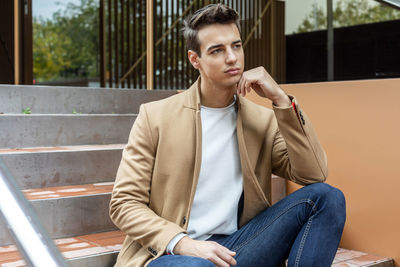 Young man using mobile phone while sitting on chair