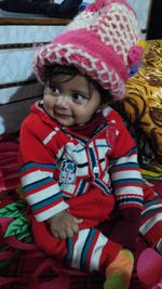High angle view of cute baby wearing warm clothing sitting on bed at home