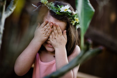 Young girl with flower crown covering eyes