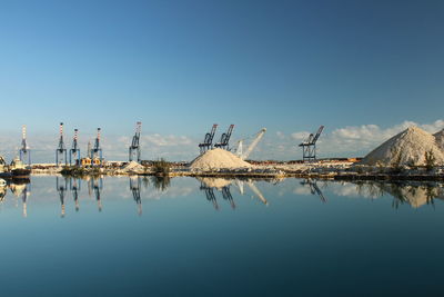 Reflection of built structure in water against clear blue sky