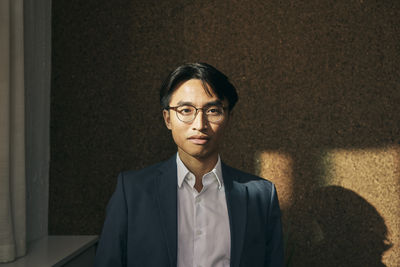 Portrait of young man standing against wall