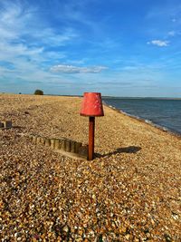 Red umbrella on beach against sky