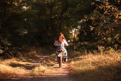 Rear view of person riding motorcycle in forest