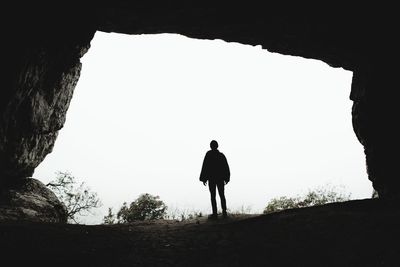 Rear view of silhouette man standing in cave