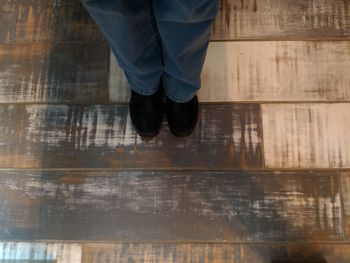 Low section of man standing on wooden floor