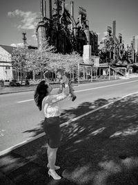 Side view of mother picking up daughter while standing on road