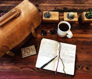 High angle view of book and pen with coffee by bag on table