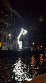 Illuminated buildings by river at night