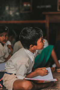 Side view of boy studying while sitting at school