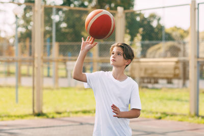 Boy playing with basketball in court