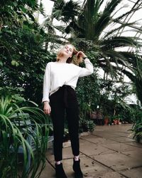 Full length of young woman standing on palm tree