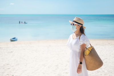 Woman wearing mask standing on beach by sea