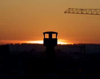 Silhouette of communications tower against sunset sky