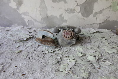 Damaged telephone against wall in abandoned building
