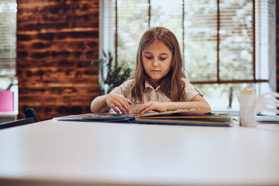 Girl learning, playing, doing puzzles and reading book in after school club. primary school