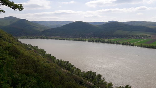 Scenic view of river by mountains against sky