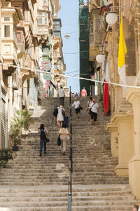 Rear view of people walking on street amidst buildings in city