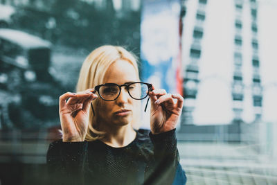 Portrait of young woman holding eyeglasses