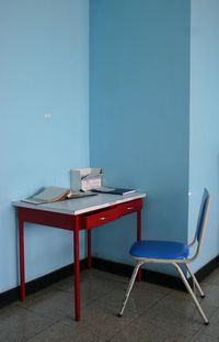 Table and chair against blue wall