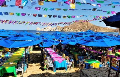 Multi colored flags hanging at beach against sky