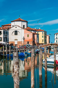 Sailboats moored in harbor against buildings in city