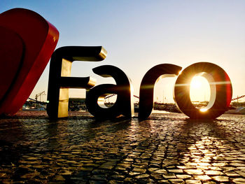 Sun shining over river against sky during sunset