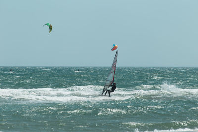 Person windsurfing against clear sky